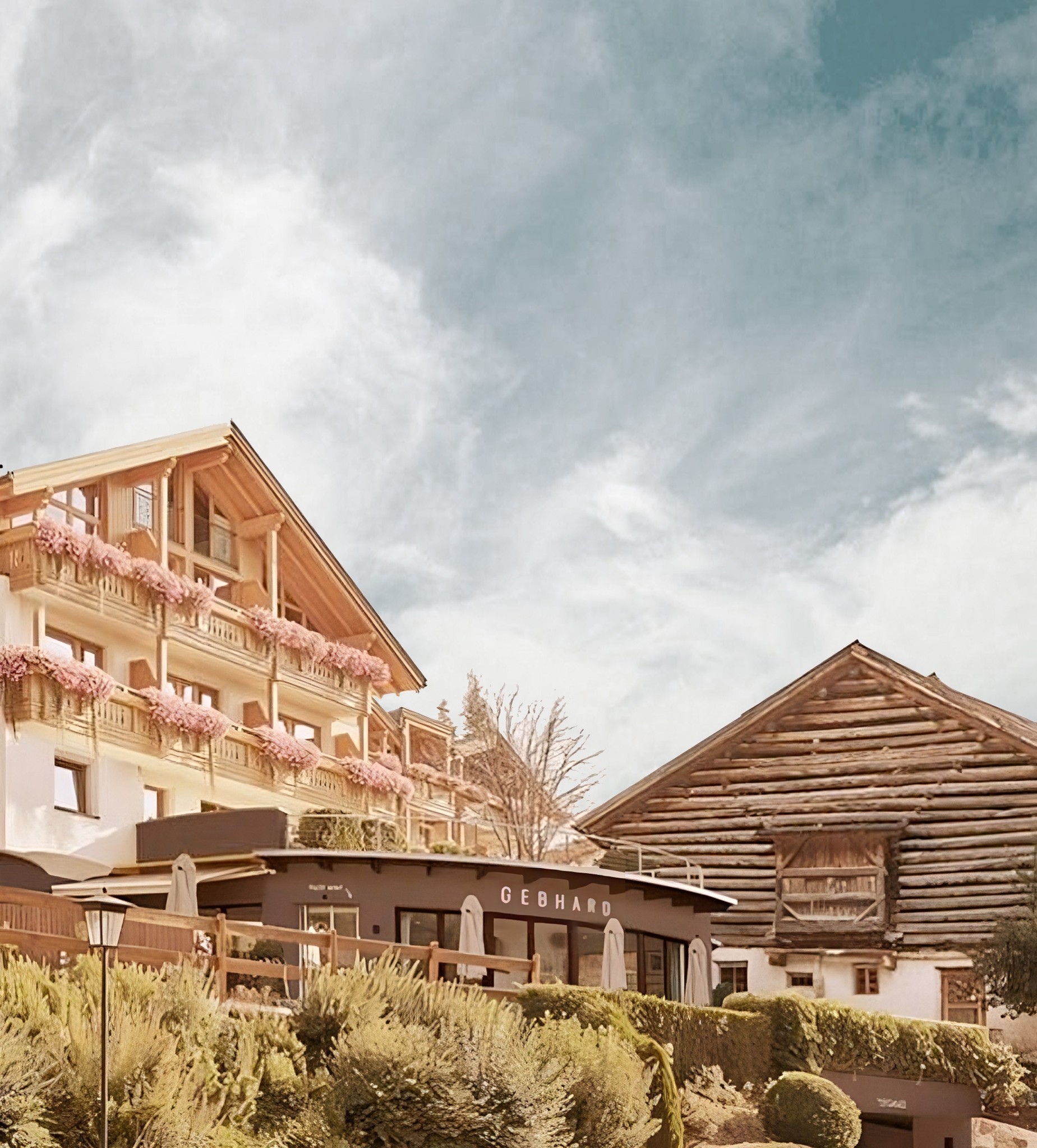 Fassade des Hotel Gebhard mit hölzernen Balkonen vor blauem Himmel.
