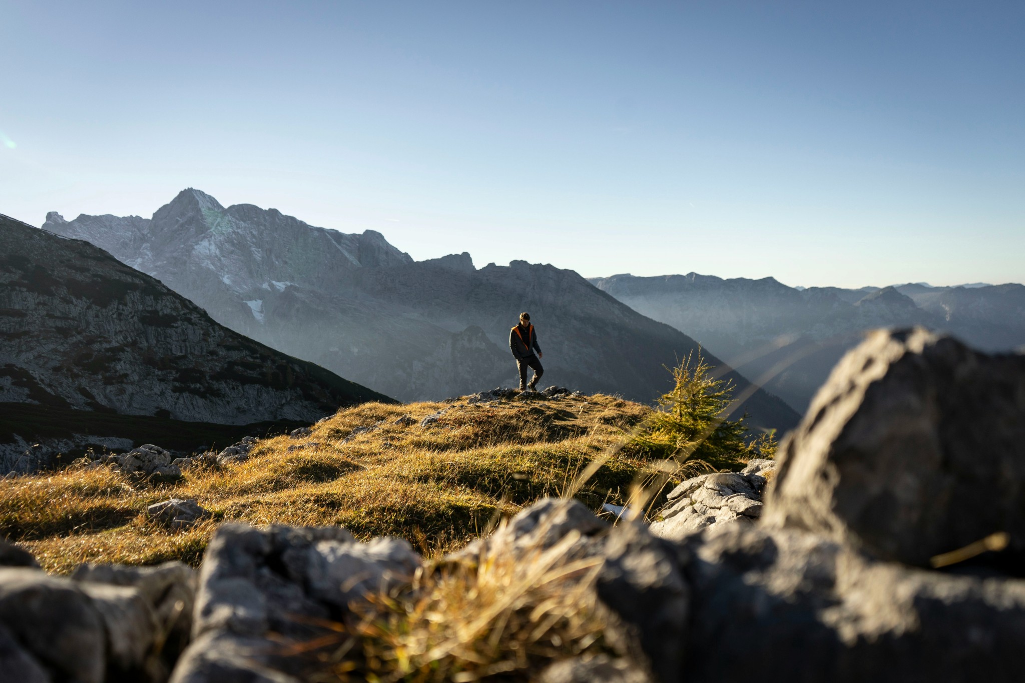 Wanderer auf einem Bergrücken im Gegenlicht, Bergkette im Dunst.