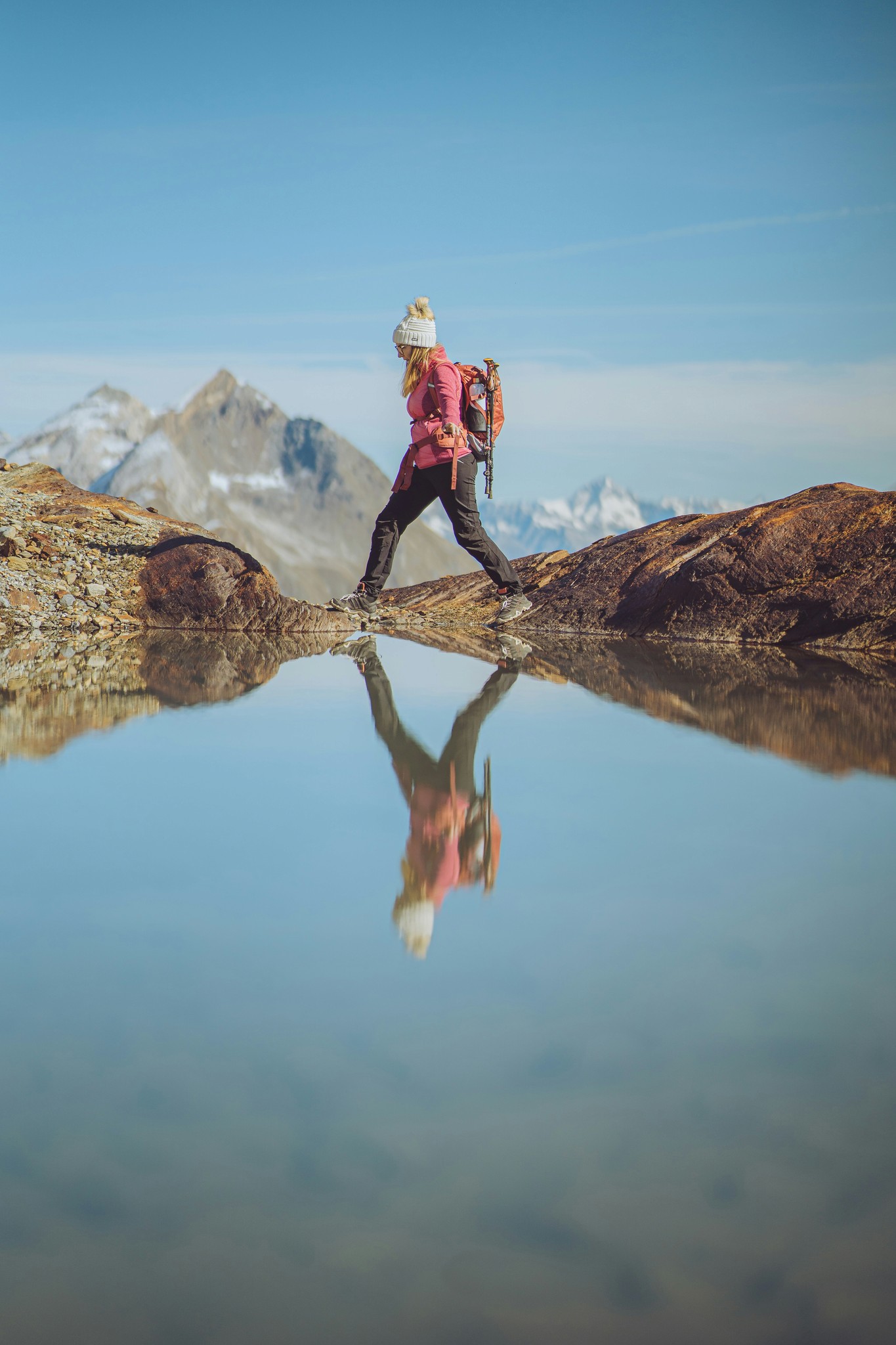 Wanderin auf einem Felsen am Bergsee, Spiegelung im stillen Wasser.